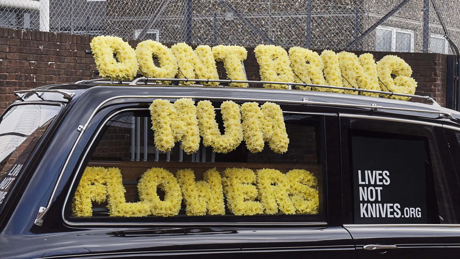 Close up of Hearse with flowers 'Dont bring mum flowers' Lives not knives dot org